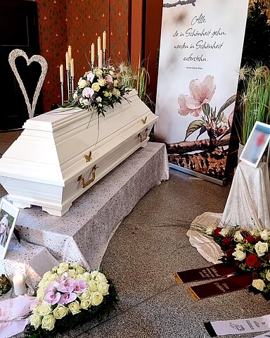 Sarg auf Traueralter mit Blumenschmuck