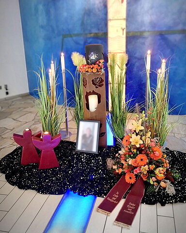 Urne auf Traueralter mit Blumenschmuck